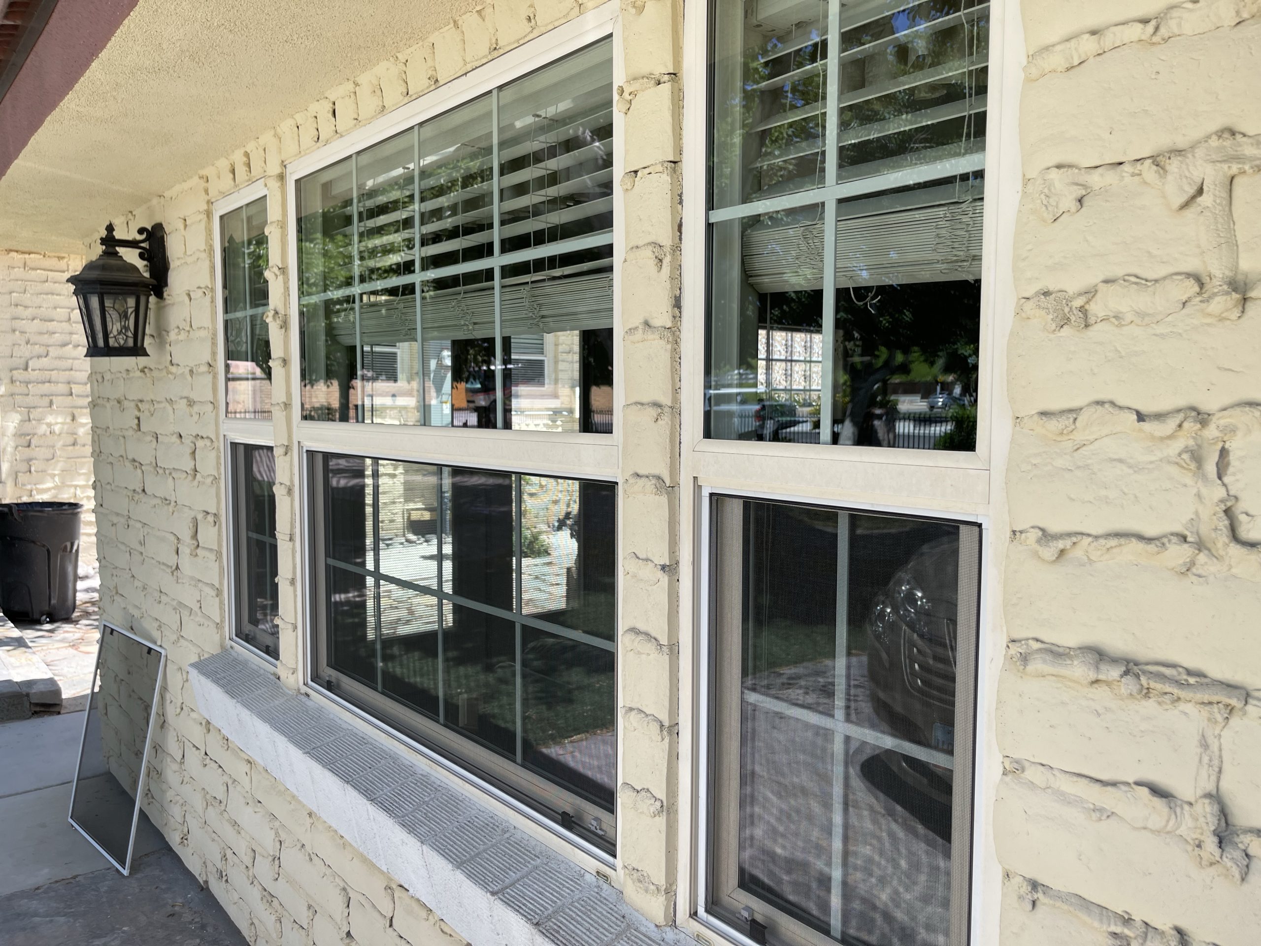 Freshly installed custom window screens and professionally cleaned windows on a stone exterior Las Vegas home